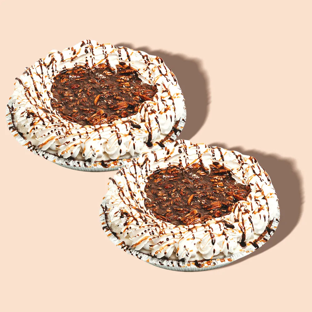 Two turtle ice cream pies with whipped cream and caramel chocolate drizzle.