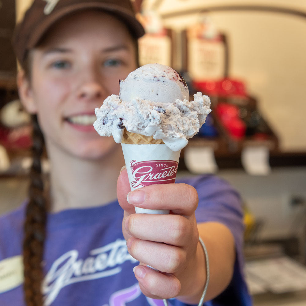 Elena's blueberry ice cream single scoop cone: a light purple ice cream with blueberries and pie crust within