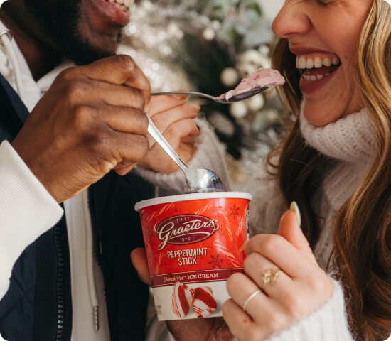 Two people enjoying a container of Graeter's peppermint stick ice cream.