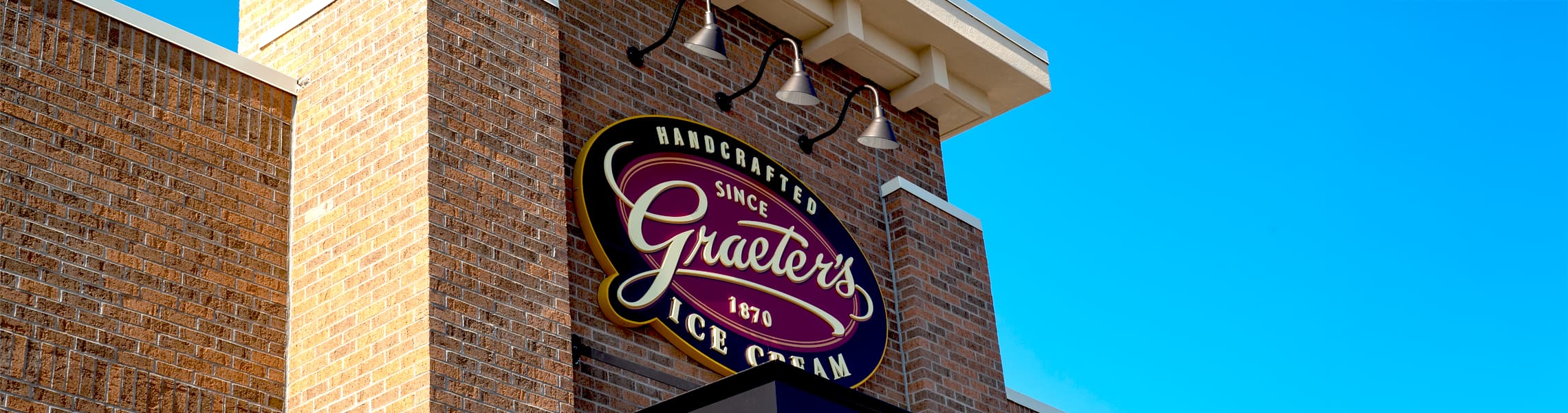 Graeter's Ice Cream sign on a brick building with a clear blue sky.